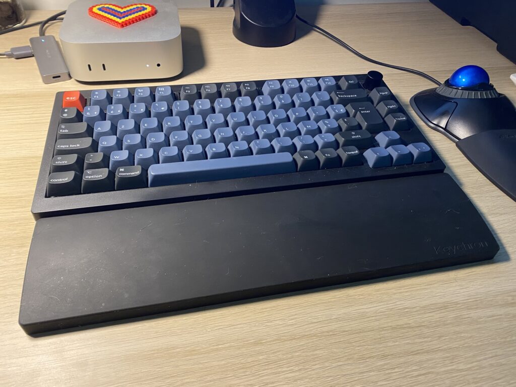 Clavier Keychron V1 Max et repose poignet en silicone sur un bureau où l'on voit également un Mac mini et un trackball Kensington.