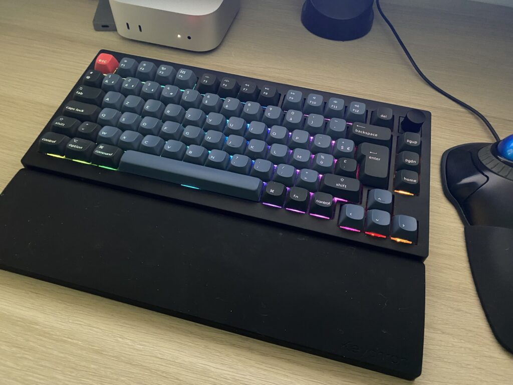 Clavier Keychron V1 Max et repose poignet en silicone sur un bureau où l'on voit également un Mac mini et un trackball Kensington.